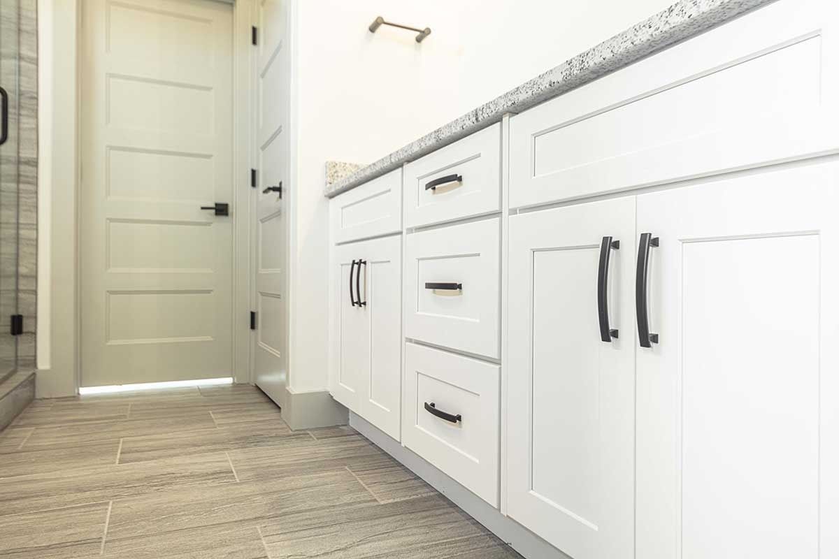 Bright bathroom with white cabinets, double sinks, and wood-look tile flooring