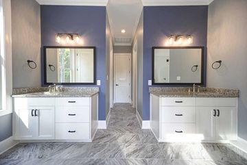 Symmetrical modern bathroom with double vanities, mirrors, sconces, and gray patterned floor