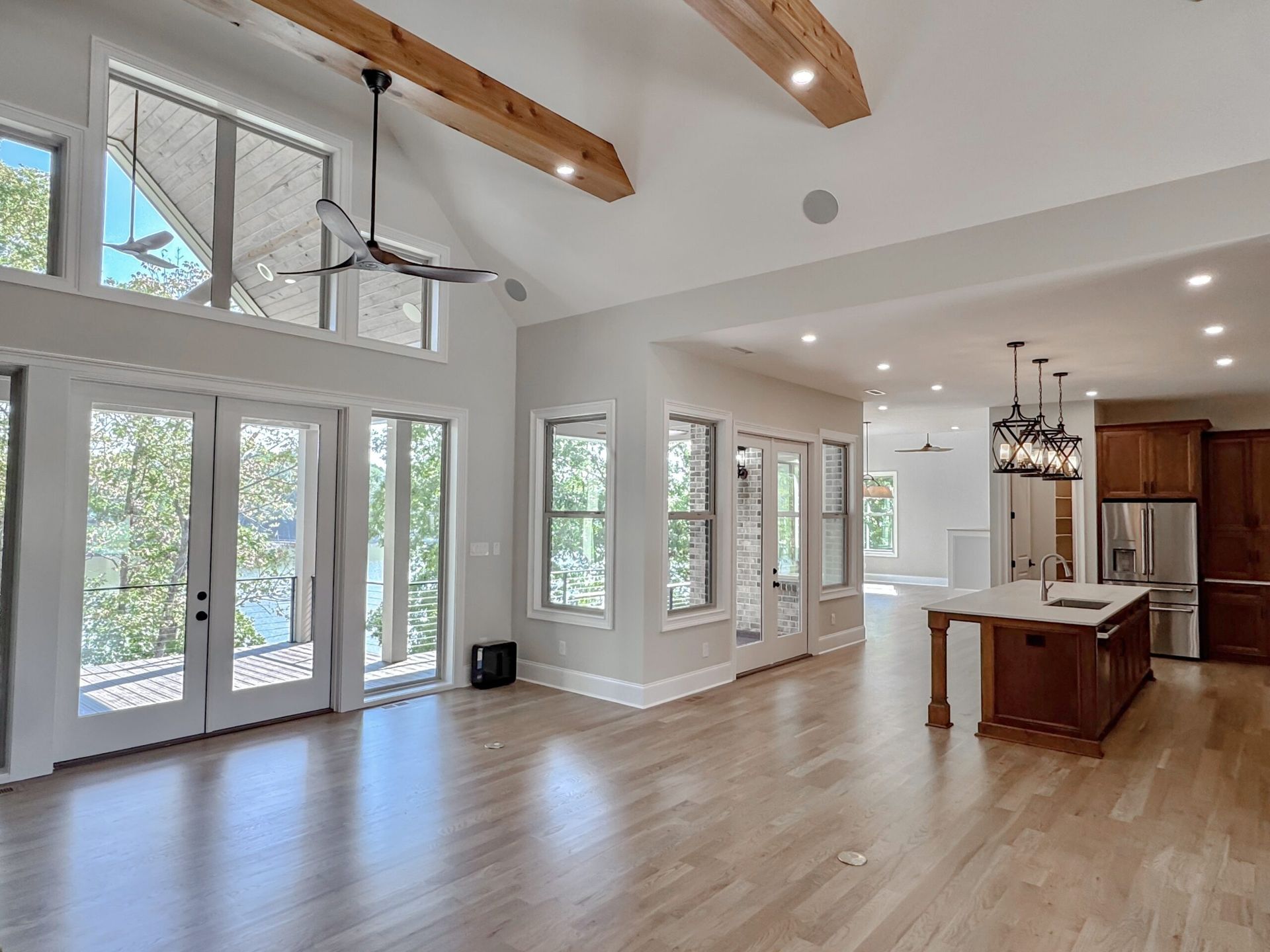 Bright open living area with vaulted ceiling, large windows, wood floors, and a kitchen island