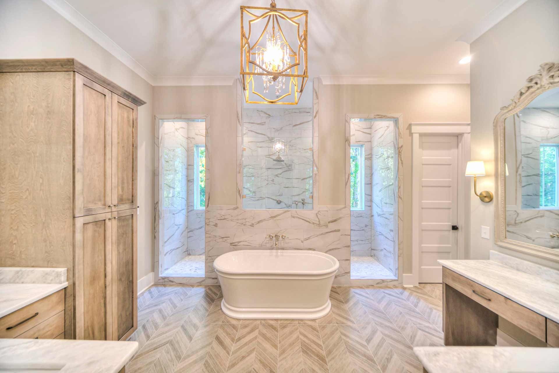 Bright modern bathroom with freestanding tub, marble shower, double vanity, and gold accents