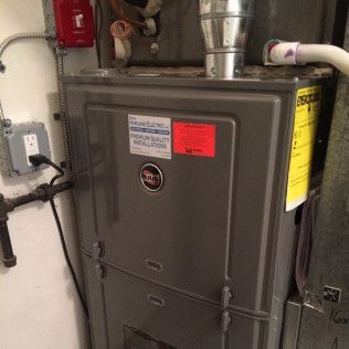A gray furnace is sitting in a room next to a wall.