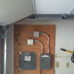 A garage with a wooden wall and electrical panels on it.