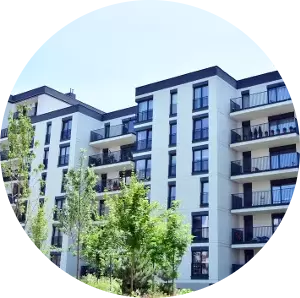 A large apartment building with balconies and trees in a circle.