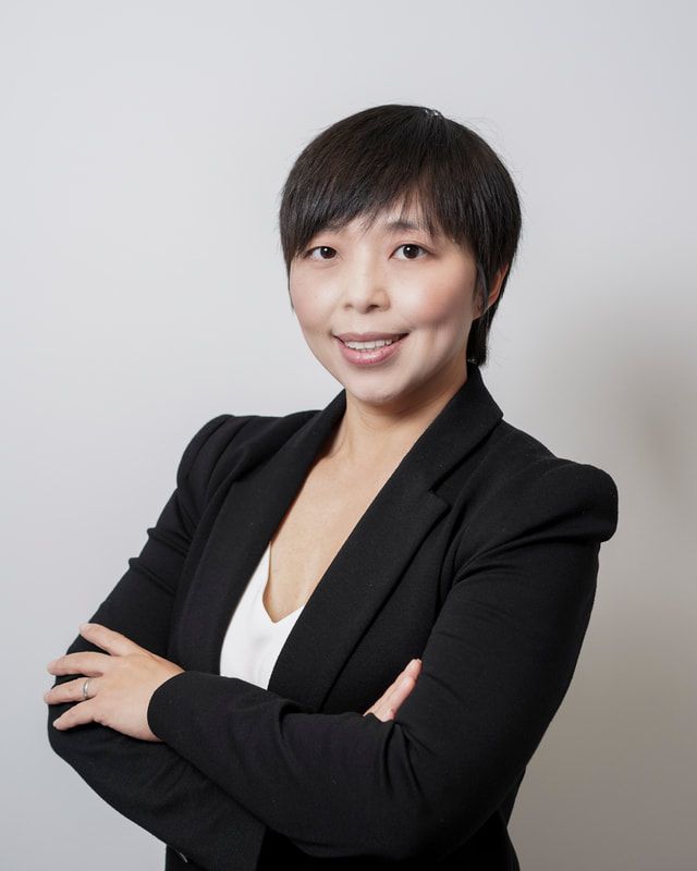 A woman in a black suit is posing for a picture with her arms crossed