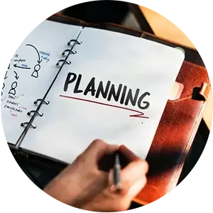 A person is writing in a notebook with the word planning written on it.