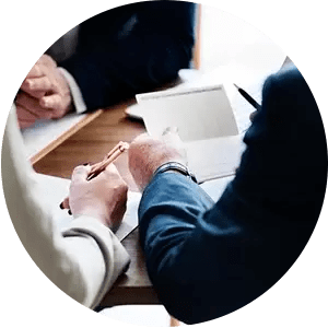 A group of people are sitting at a table writing on a piece of paper.