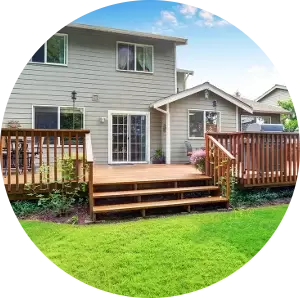 A house with a wooden deck and stairs in the backyard.