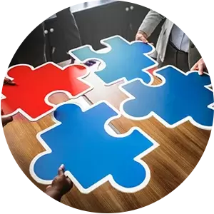 A group of people are sitting around a table with puzzle pieces on it.