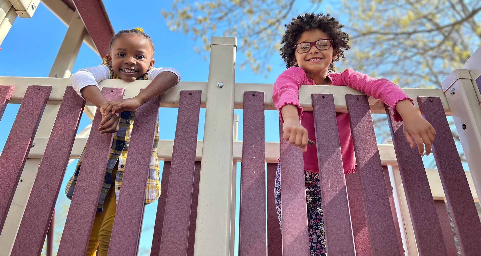 Two Montessori childs are standing next to each other on a playground.