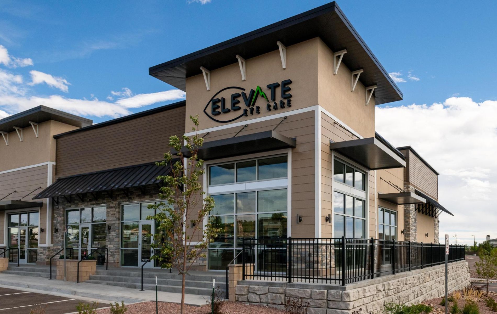 Modern commercial building with glass entrance and “ELEVATE” sign under a blue sky