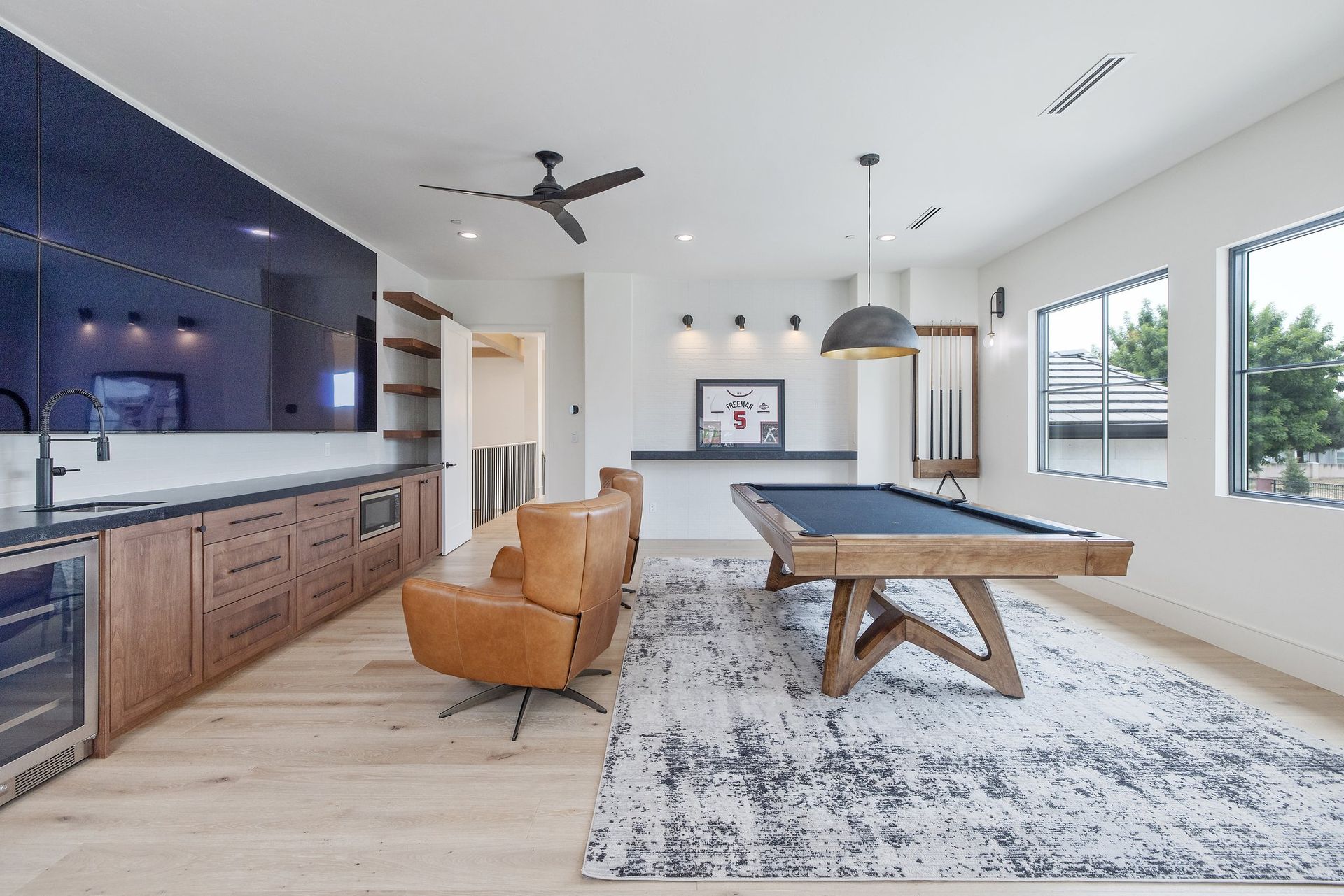 Modern open-concept kitchen and dining area with wood cabinets, blue island, pendant lights, and a table on a rug