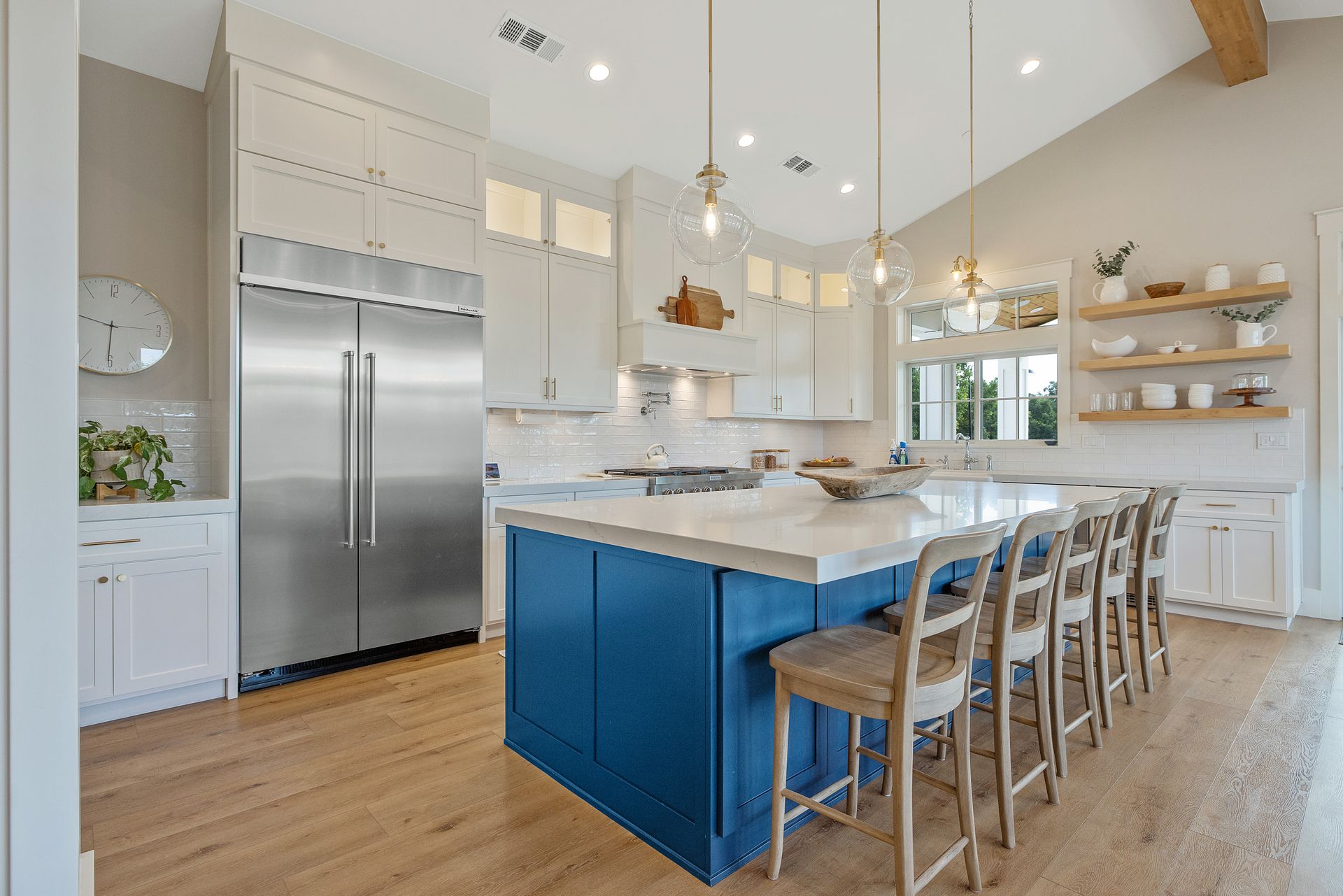 Bright modern kitchen with blue island, stainless steel fridge, and bar stools