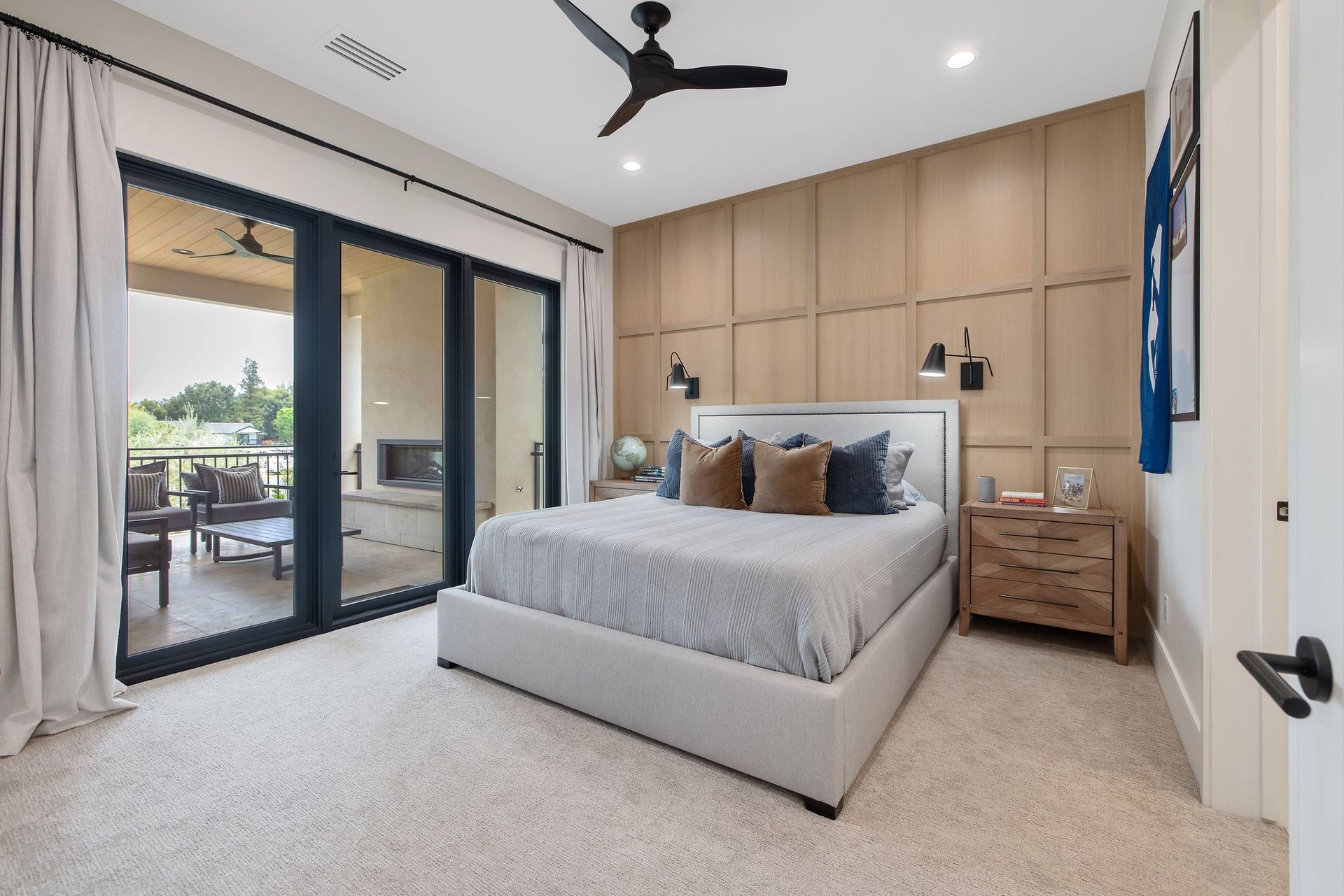 Modern bedroom with a king bed, wood accent wall, and sliding doors to a patio