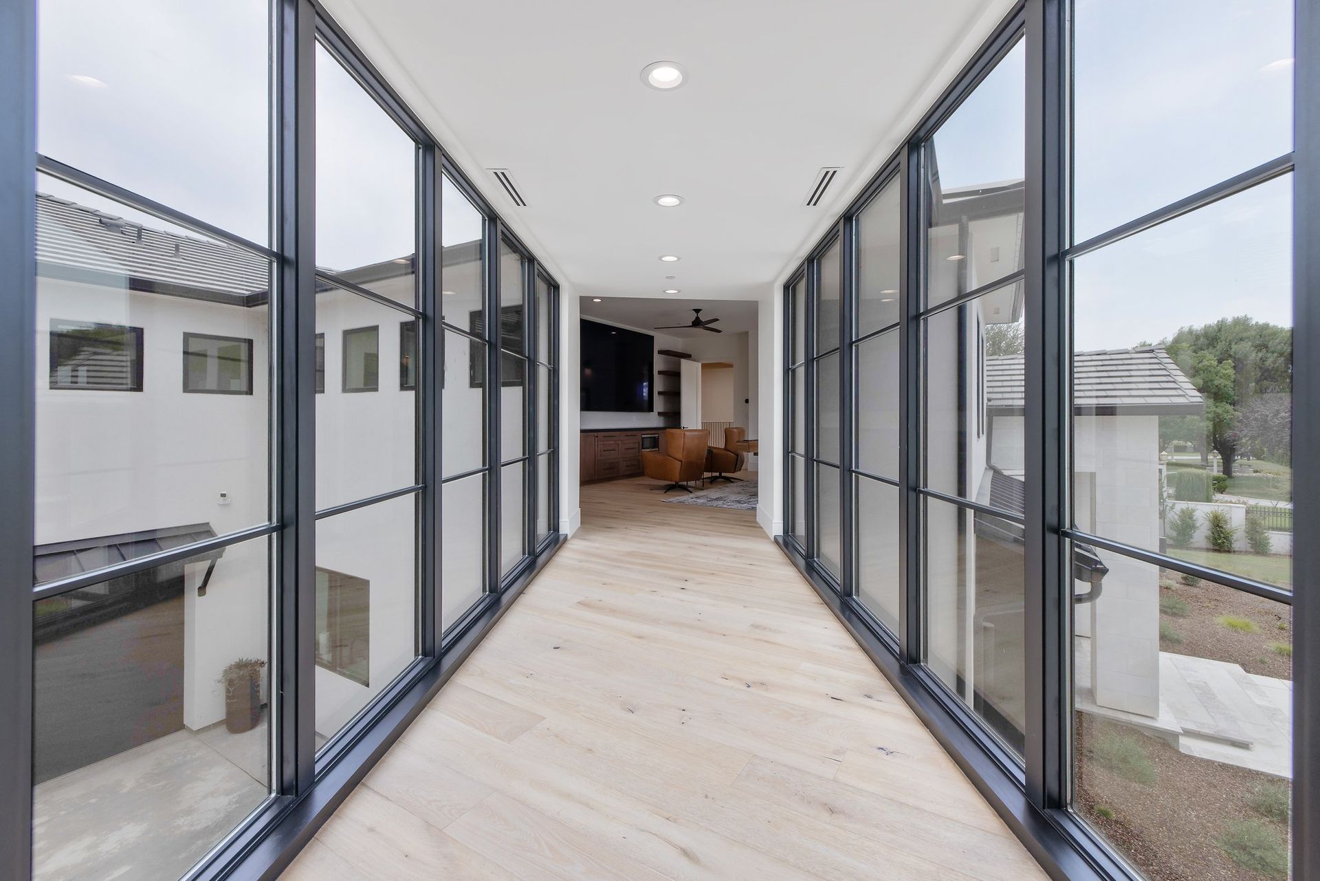 Bright hallway with floor-to-ceiling glass doors and windows leading to a modern living area