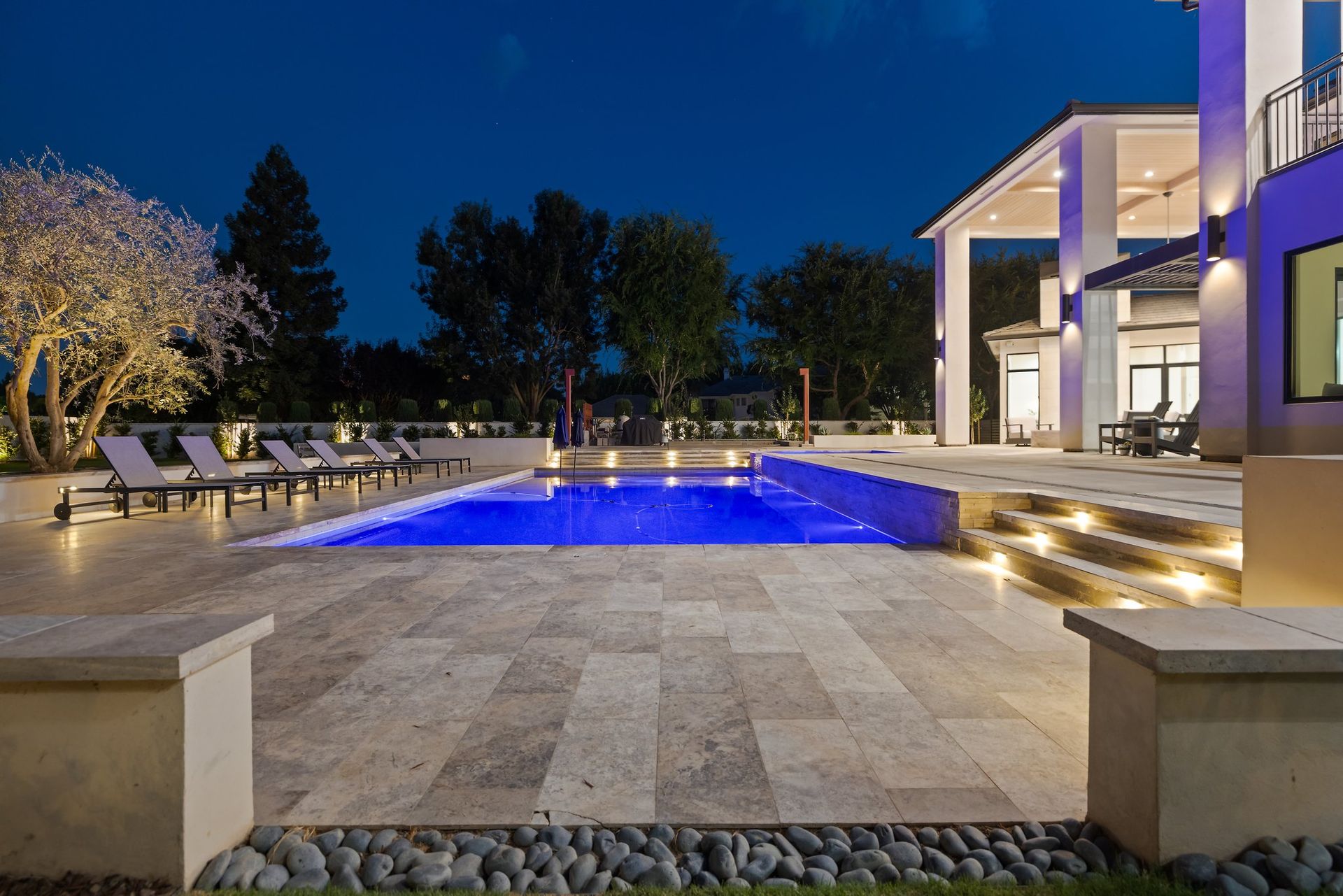 Modern house patio with lit blue swimming pool at dusk