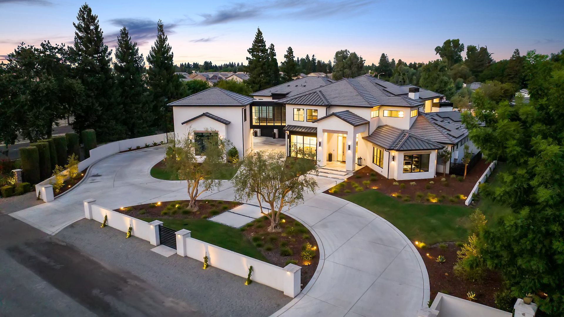 Modern luxury house with curved driveway and landscaped grounds at dusk
