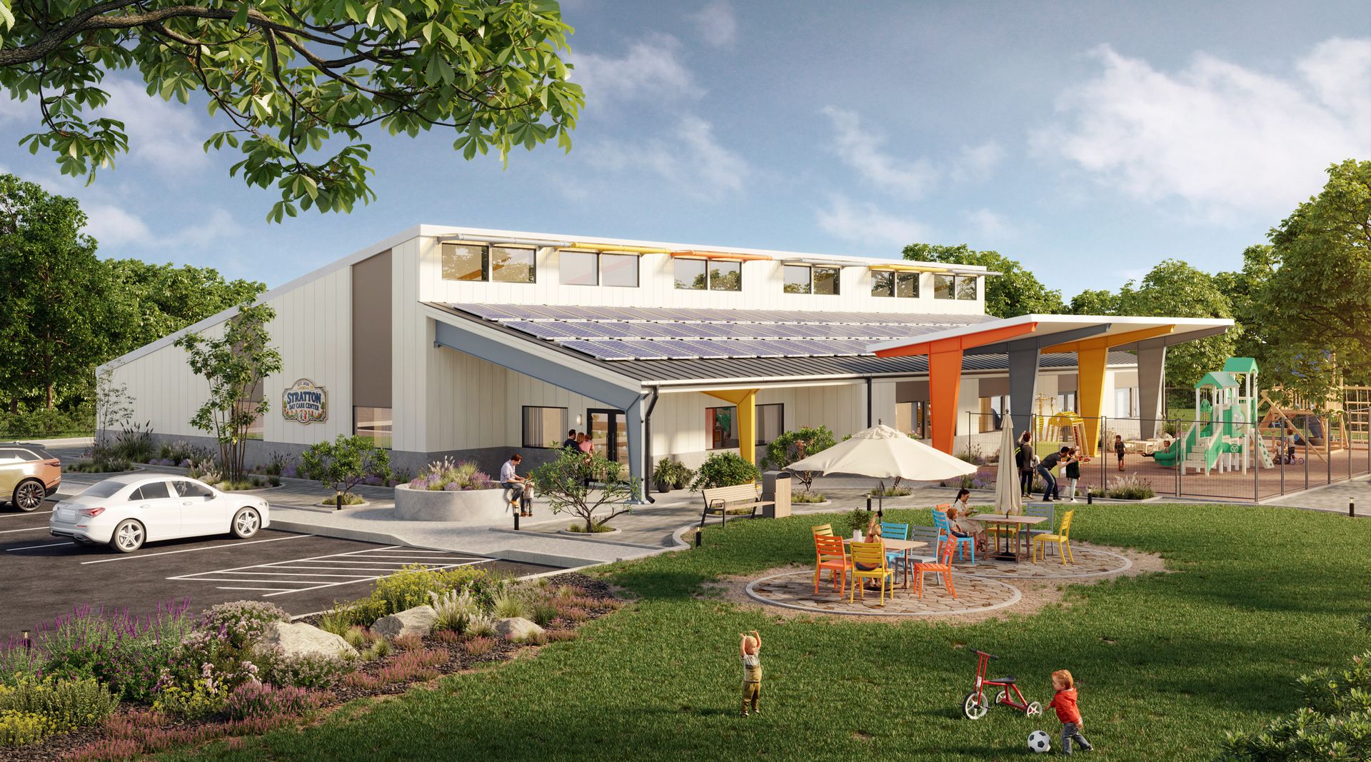 Modern school building with playground, outdoor seating, and parked cars under a clear sky