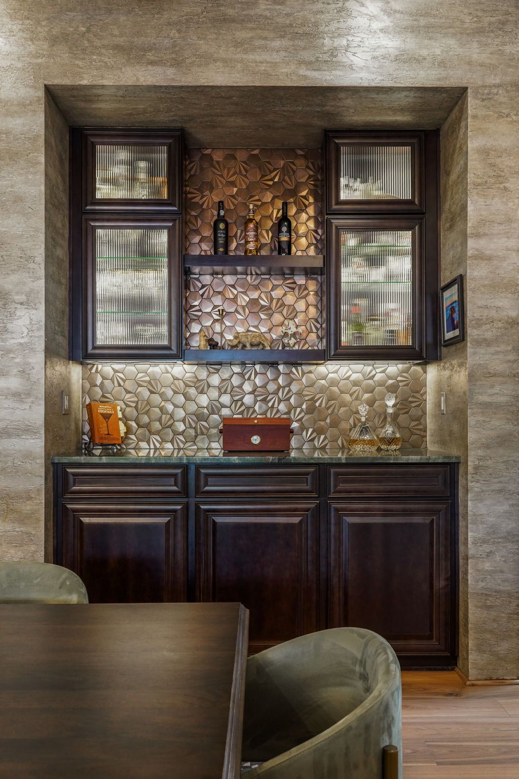 Built-in dark wood bar cabinet with mosaic backsplash, shelves, and countertop in a cozy room