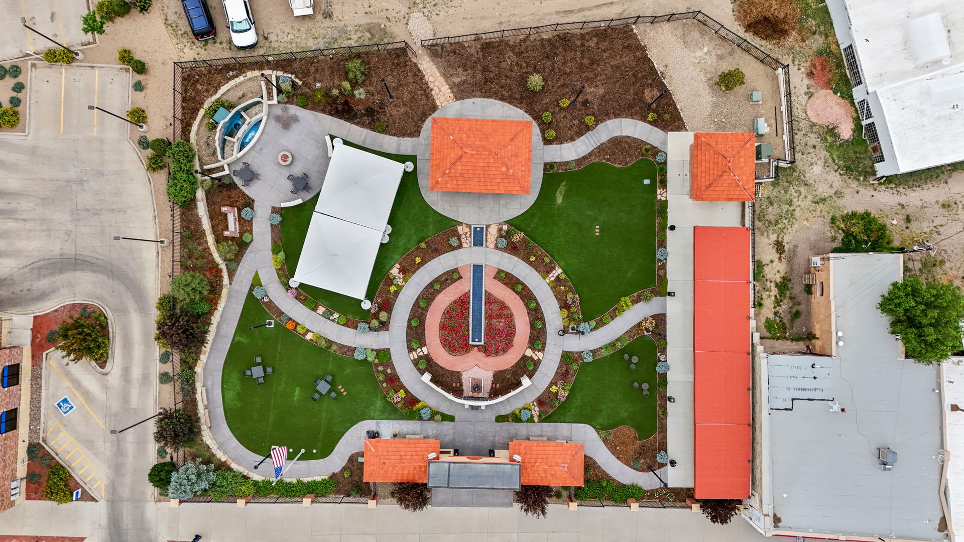 Aerial view of a landscaped courtyard with circular paths, red-roofed buildings, and green lawns