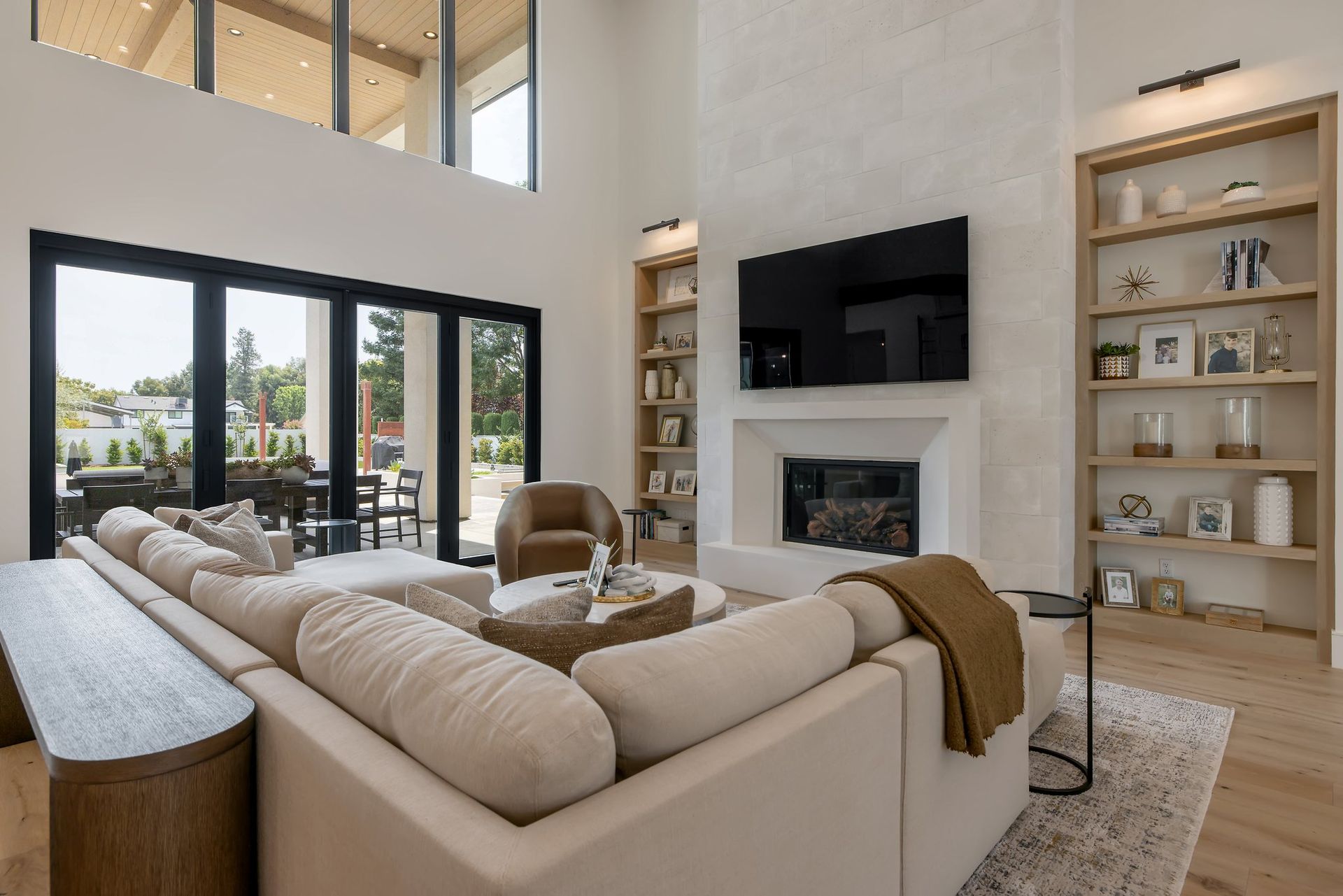 Bright modern living room with beige sectional, fireplace, TV, and large sliding glass doors