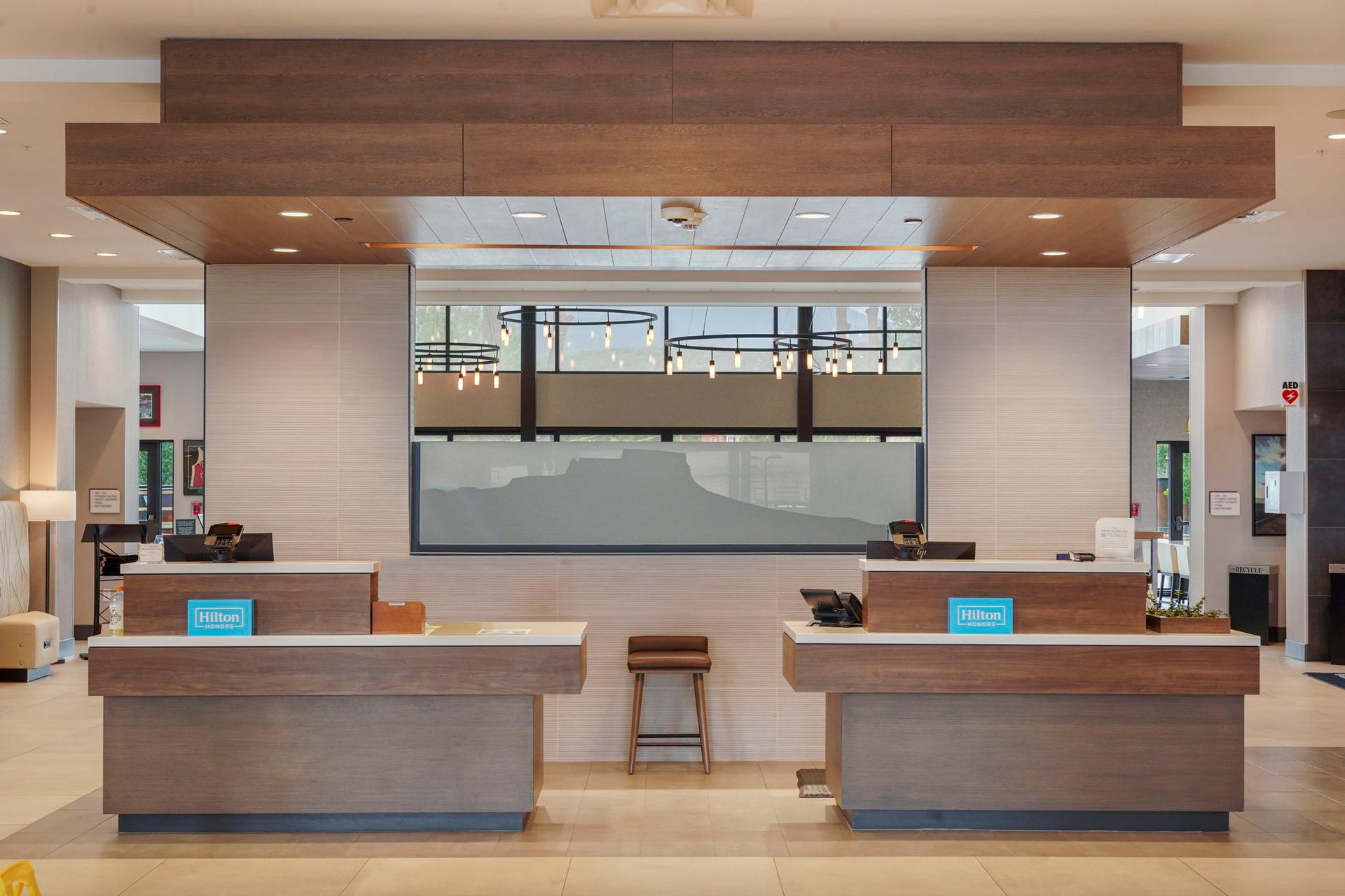 Modern hotel reception desk with two wooden counters and a glass wall behind them