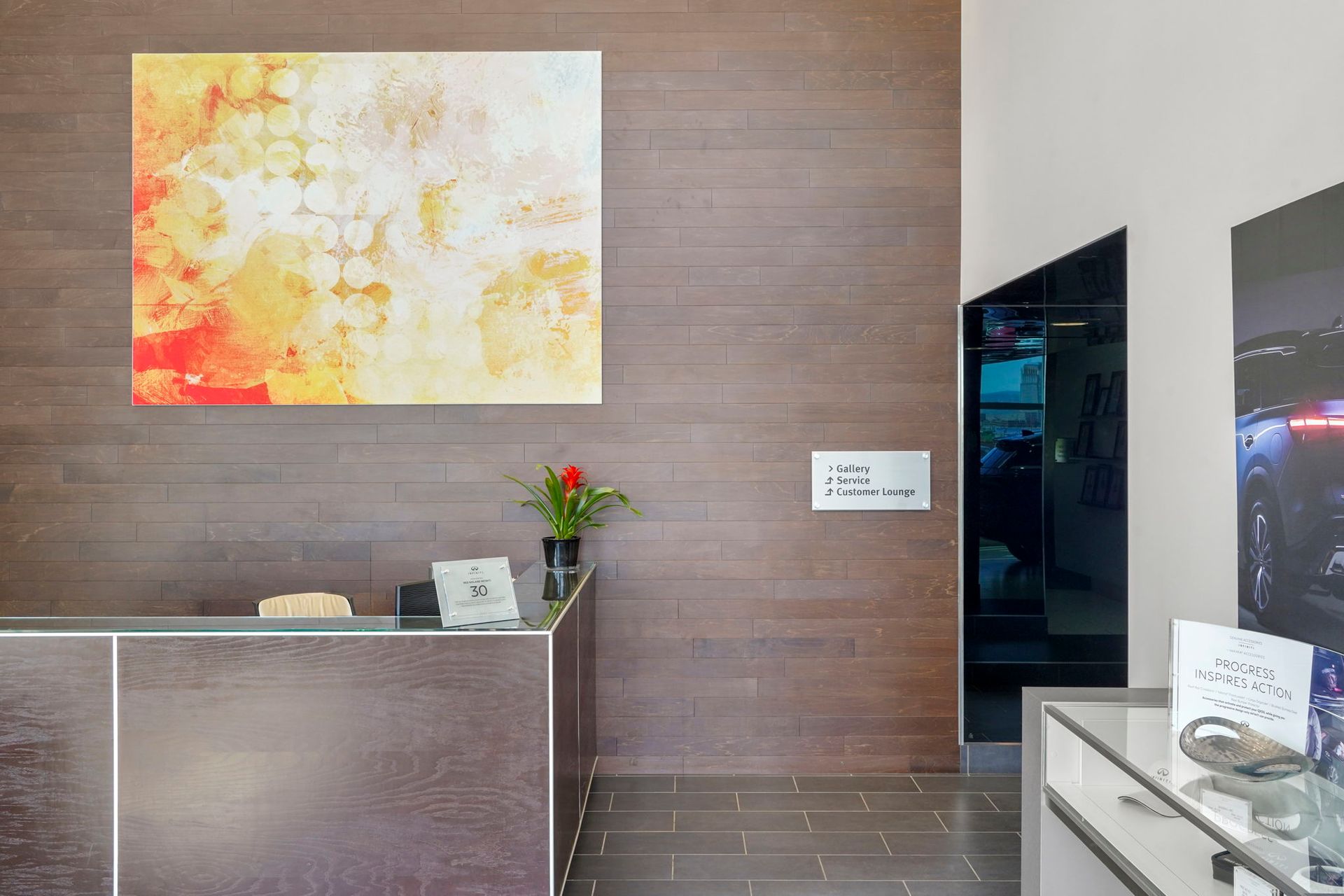 Hotel lobby reception desk with abstract wall art, flowers, and a hallway entrance