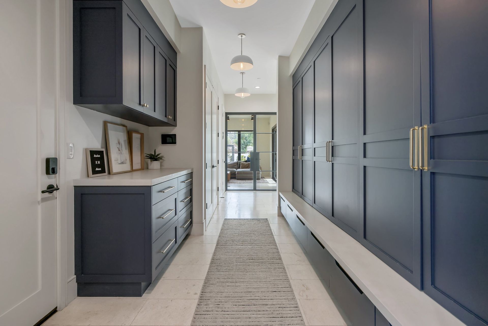 Modern hallway with dark blue built-in cabinets, white walls, and a runner rug