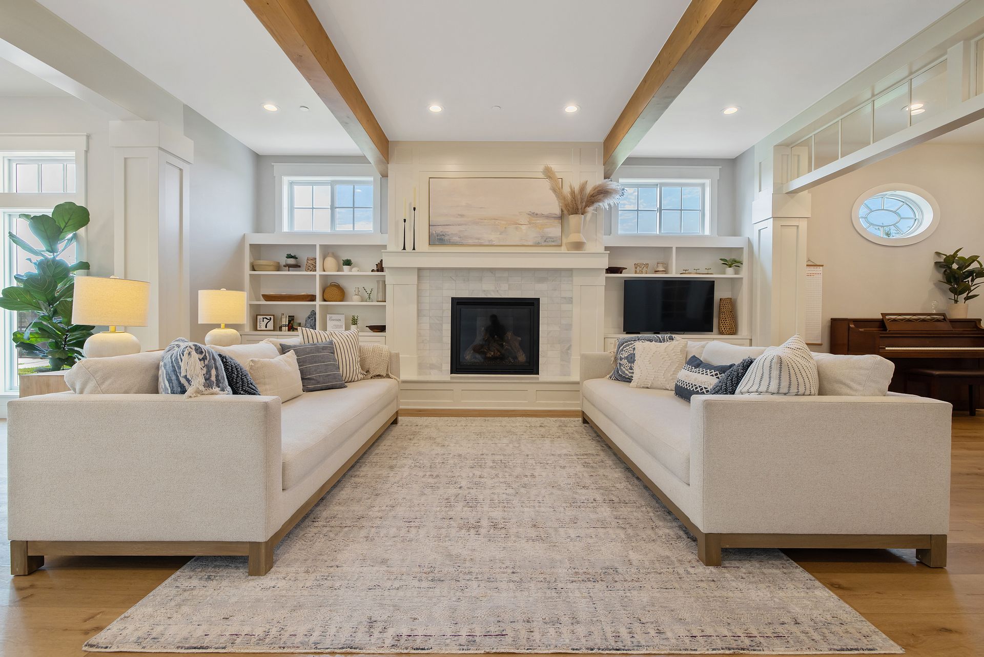Bright living room with two beige sofas facing a fireplace and built-in shelves