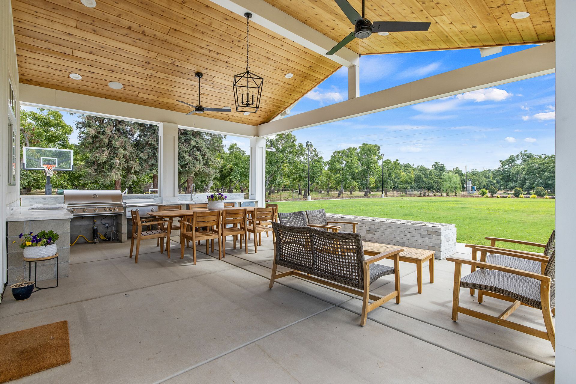 Covered patio with wooden dining table and seating overlooking a green golf course