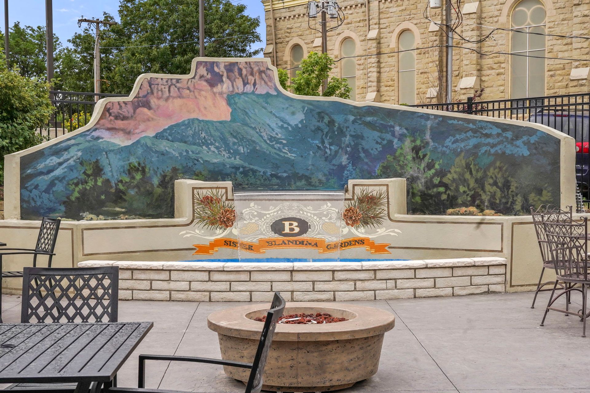 Outdoor mural bench with painted mountain and river scene in a courtyard