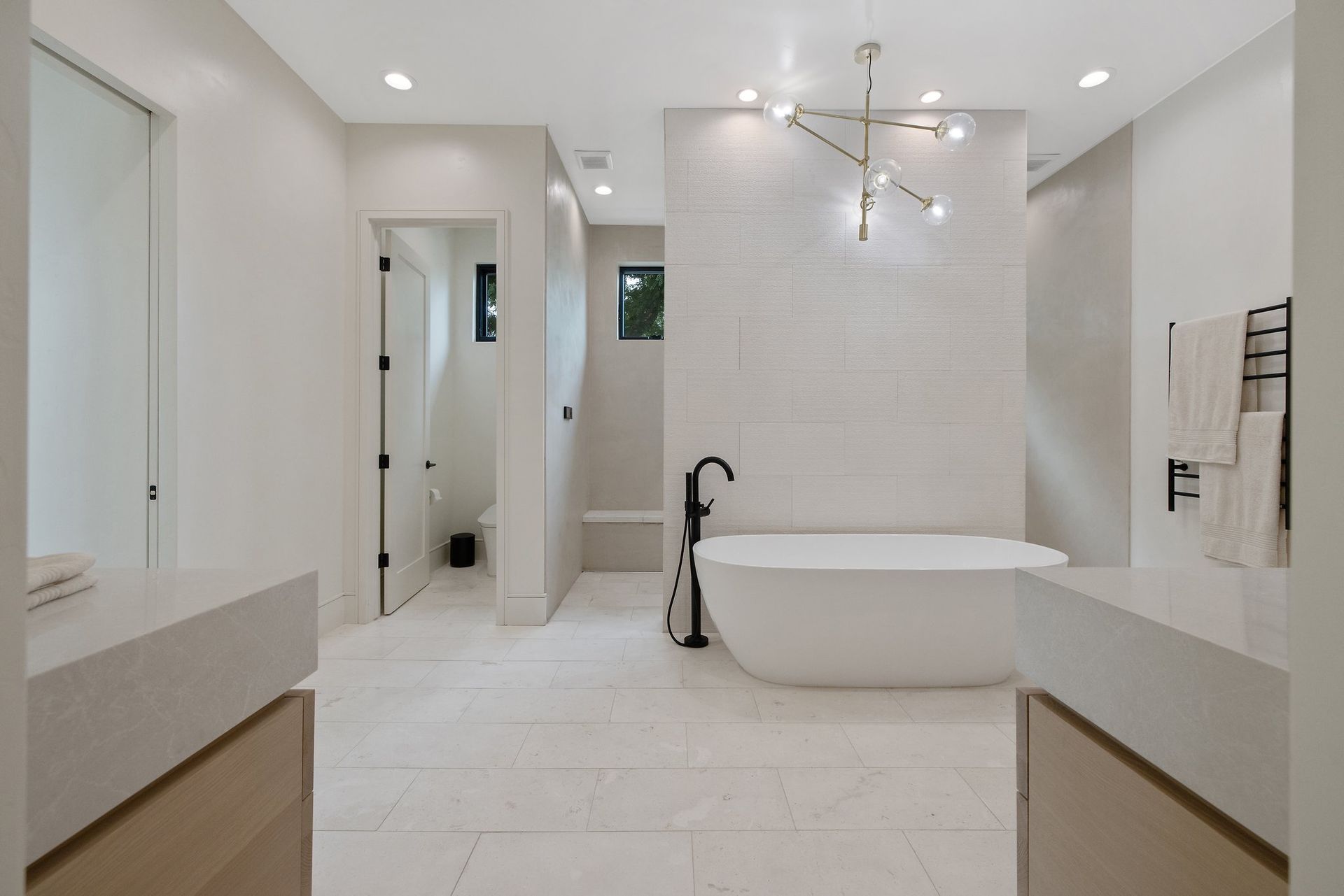 Modern white bathroom with freestanding tub, walk-in shower, and dual sinks