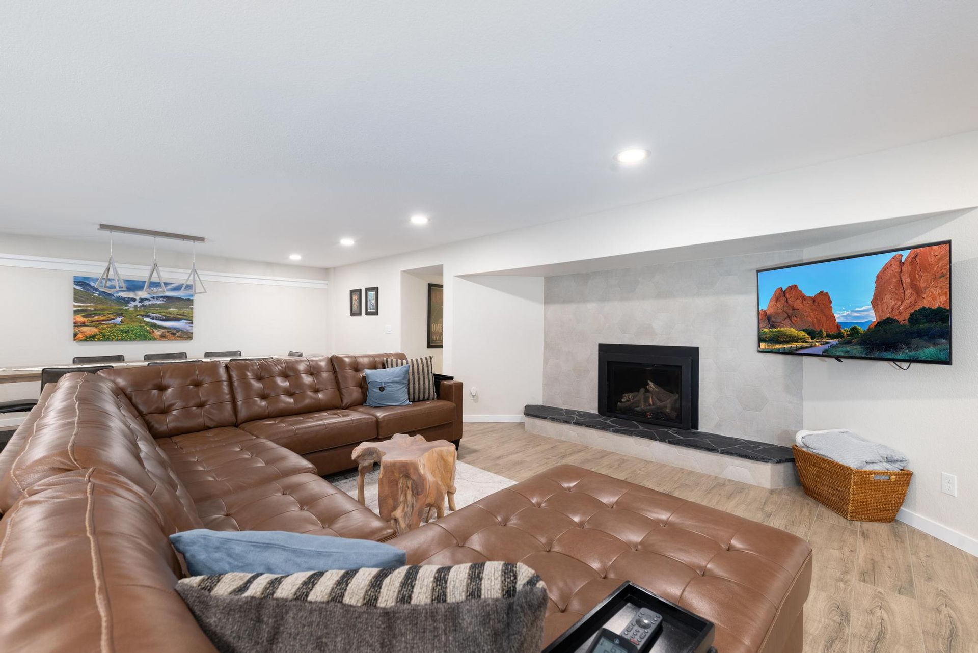 Modern living room with brown sectional sofa, fireplace, and wall-mounted TV above light carpet.
