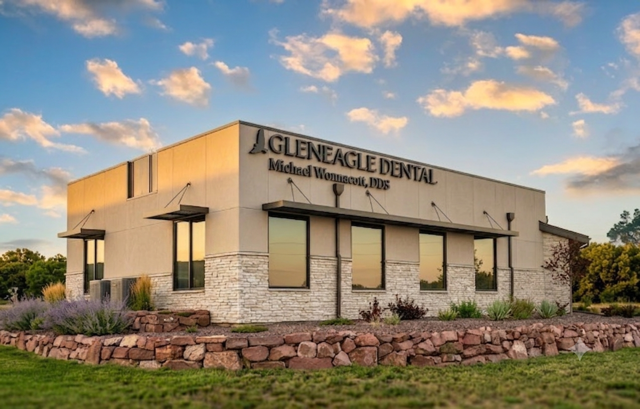 Exterior of Glen Eagle Dental office at sunset with beige walls, stone trim, and landscaped rock border