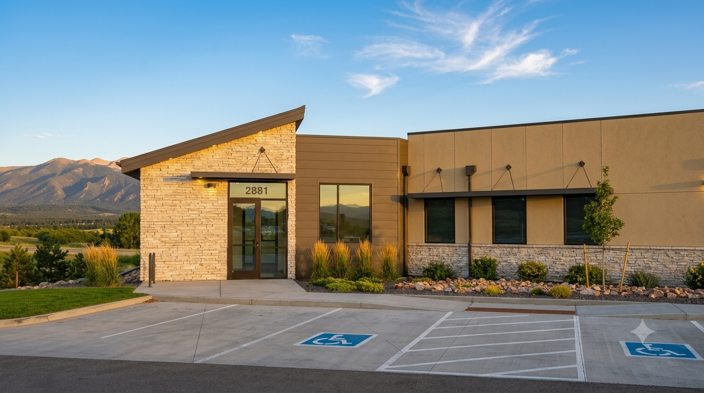 Modern office building with accessible parking spaces and mountain view at sunset