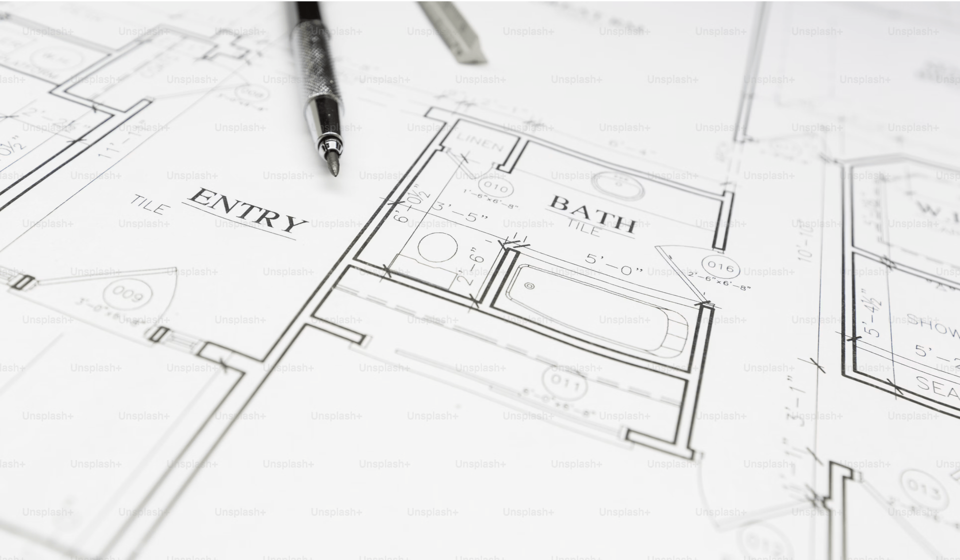 Architectural floor plan sketched on paper with a pencil nearby, showing labeled rooms and measurements