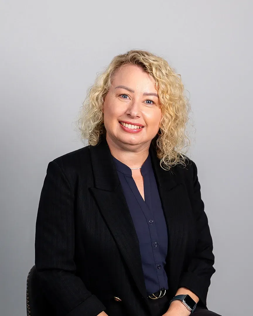 Portrait of a smiling woman in a black blazer against a light gray background