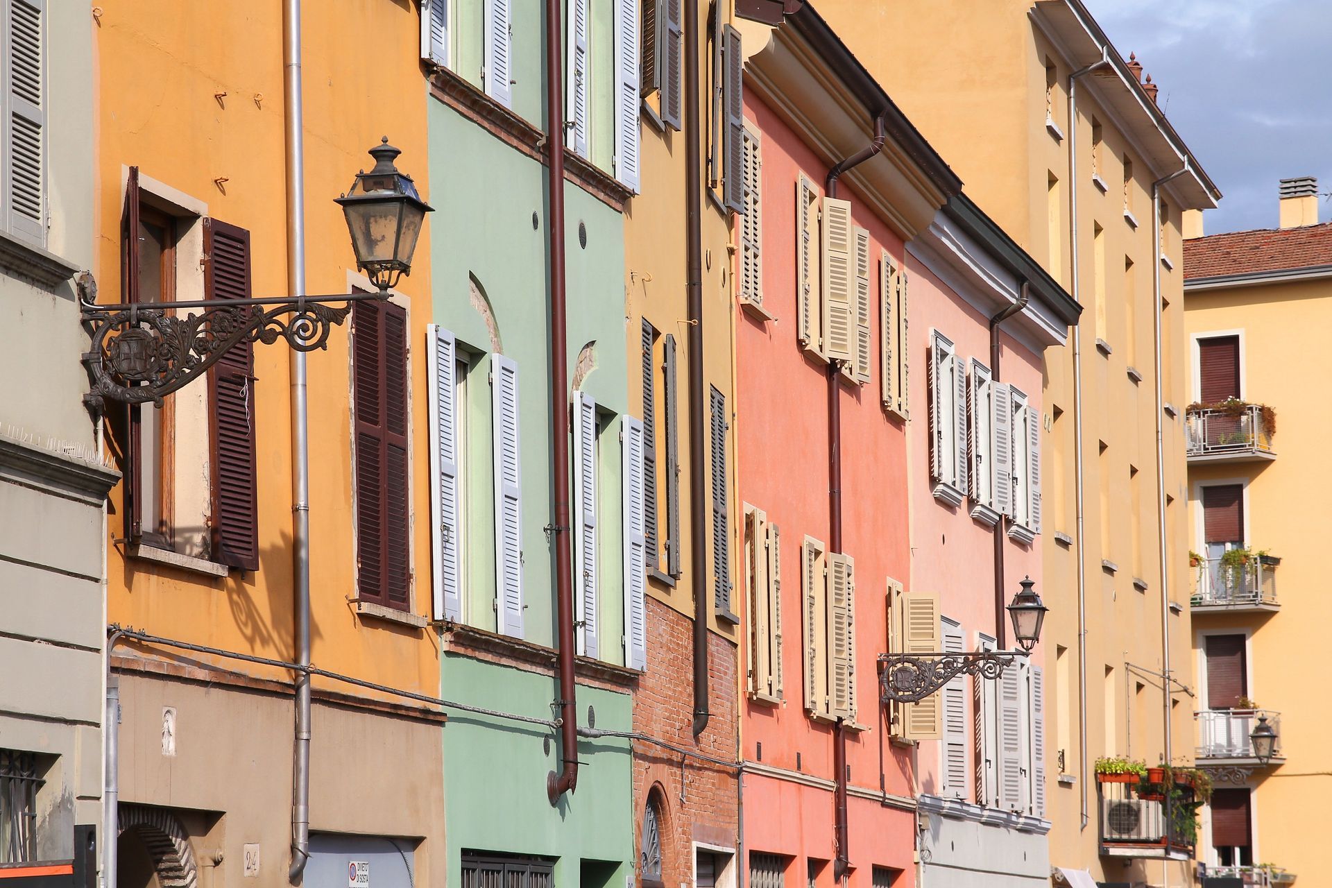 Edifici dai colori pastello con persiane e balconi lungo una stretta strada europea