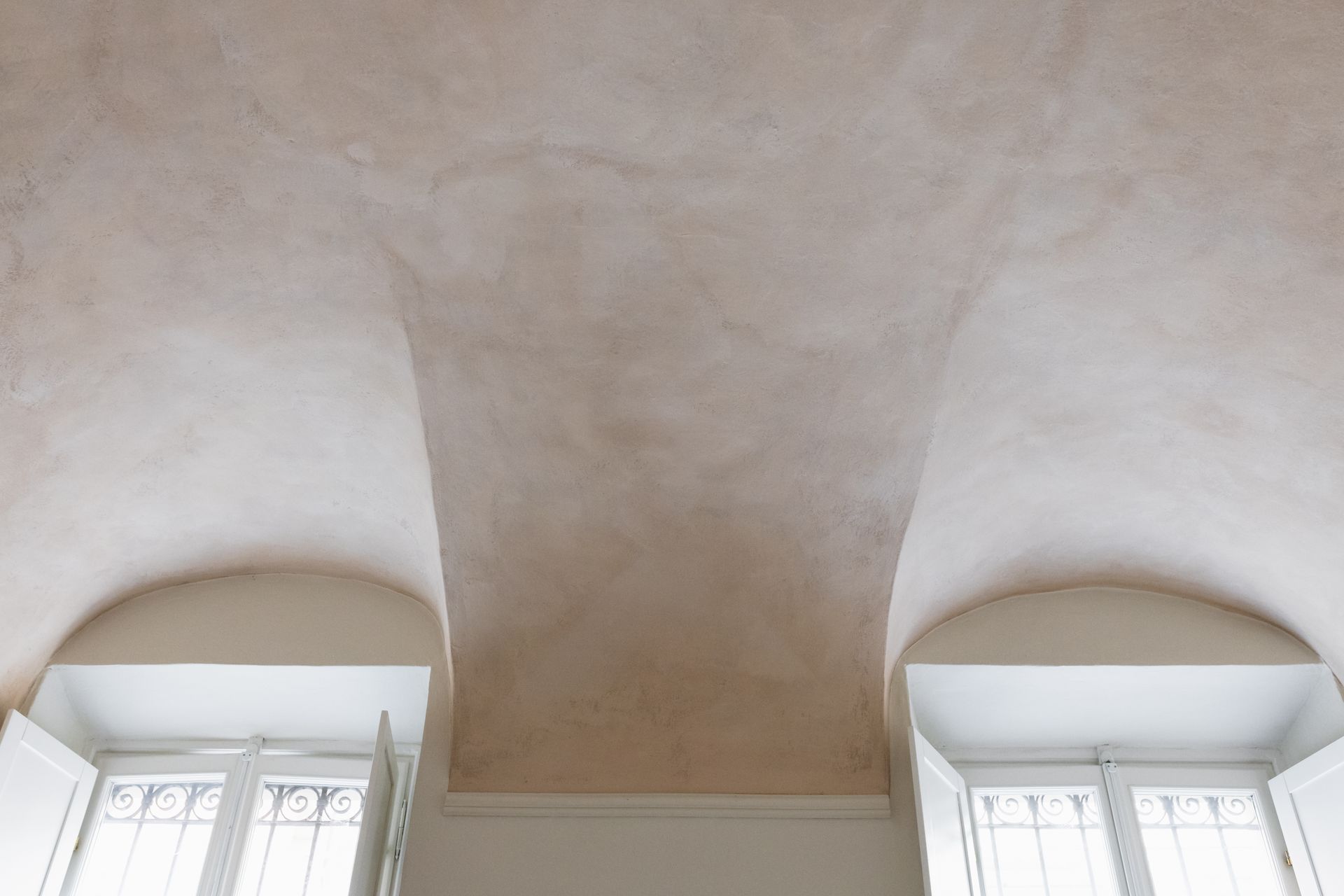 Soffitto interno con nicchia ad arco e stucco beige chiaro sopra due finestre