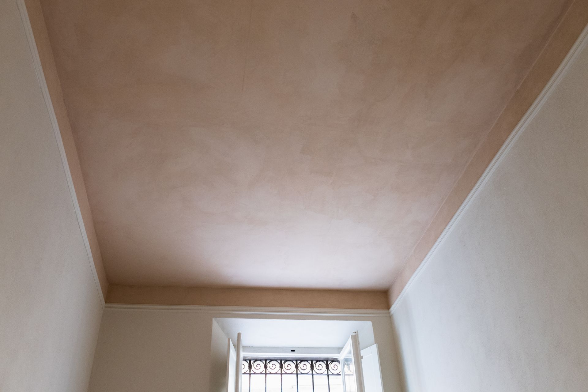 Soffitto di una piccola stanza con un pannello incassato color beige sopra una finestra