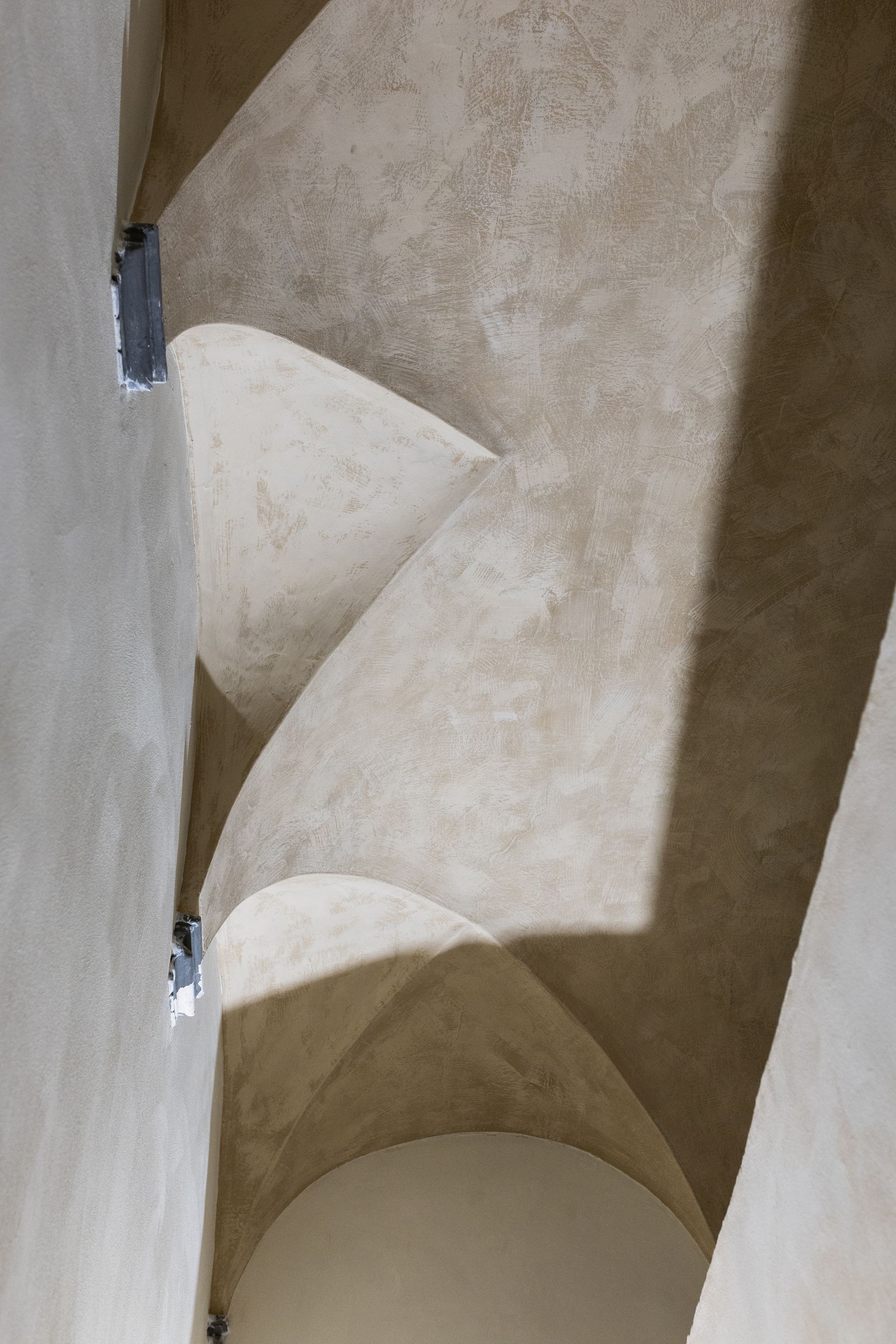 Arco in pietra con soffitto curvo e scala stretta visti dal basso