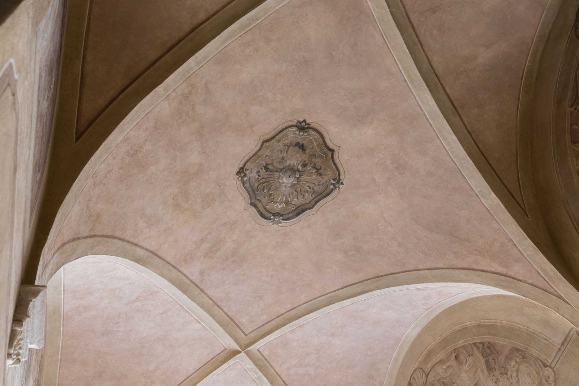 Soffitto a volta della chiesa con intonaco rosa pallido e un medaglione centrale decorativo.