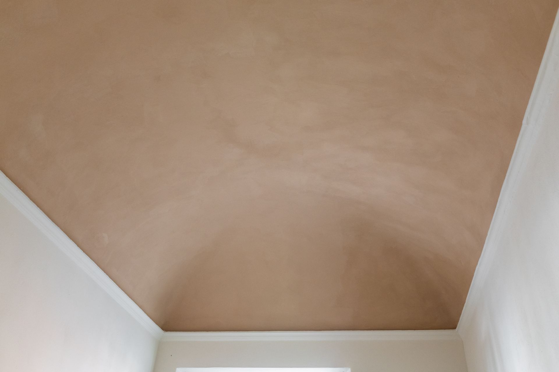 Soffitto beige con una macchia d'acqua centrale sopra pareti bianche in una stanza