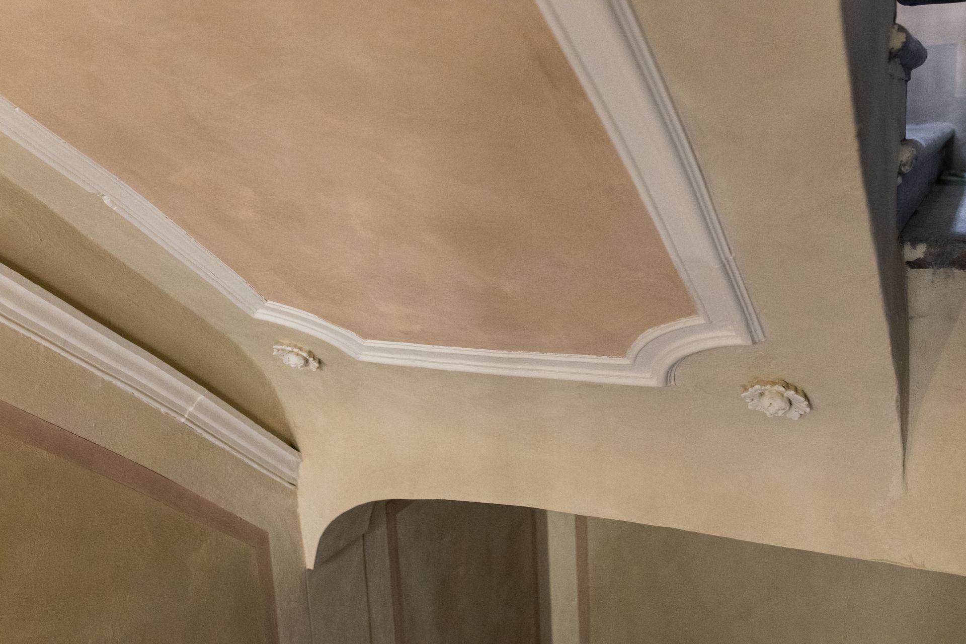 Soffitto decorativo beige con modanature bianche e dettagli di finitura incassati.