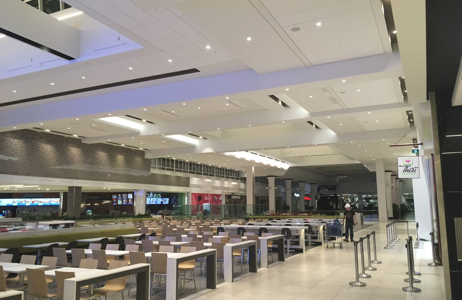 Une grande aire de restauration vide dans un centre commercial avec des tables et des chaises.