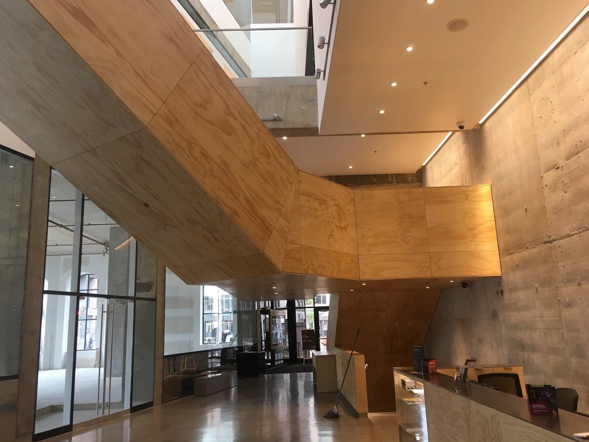 Un grand hall d'entrée avec un escalier en bois et un mur en béton