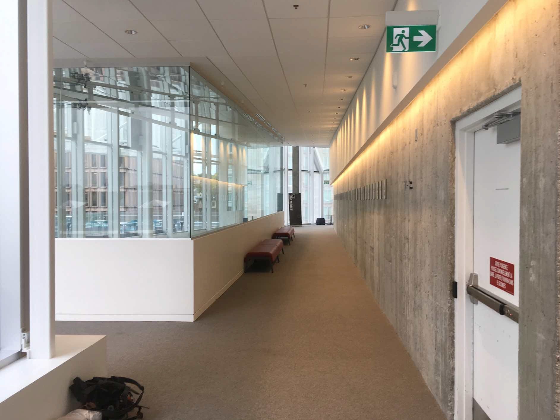 Un long couloir avec un panneau de sortie vert sur le mur