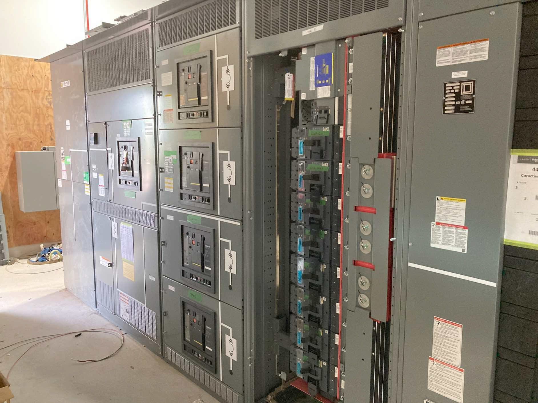 Une rangée de panneaux électriques est alignée dans une pièce.