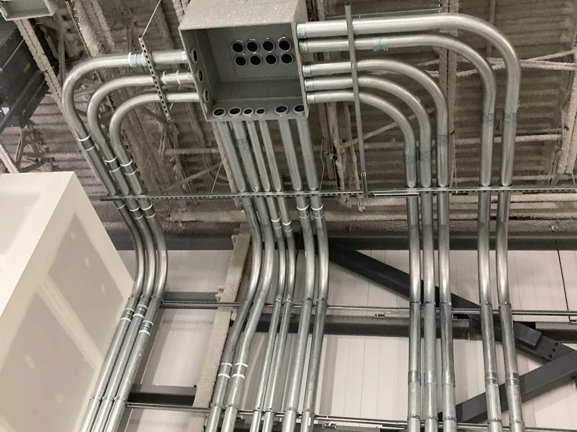 Un tas de tuyaux métalliques sont suspendus au plafond d'un immeuble.