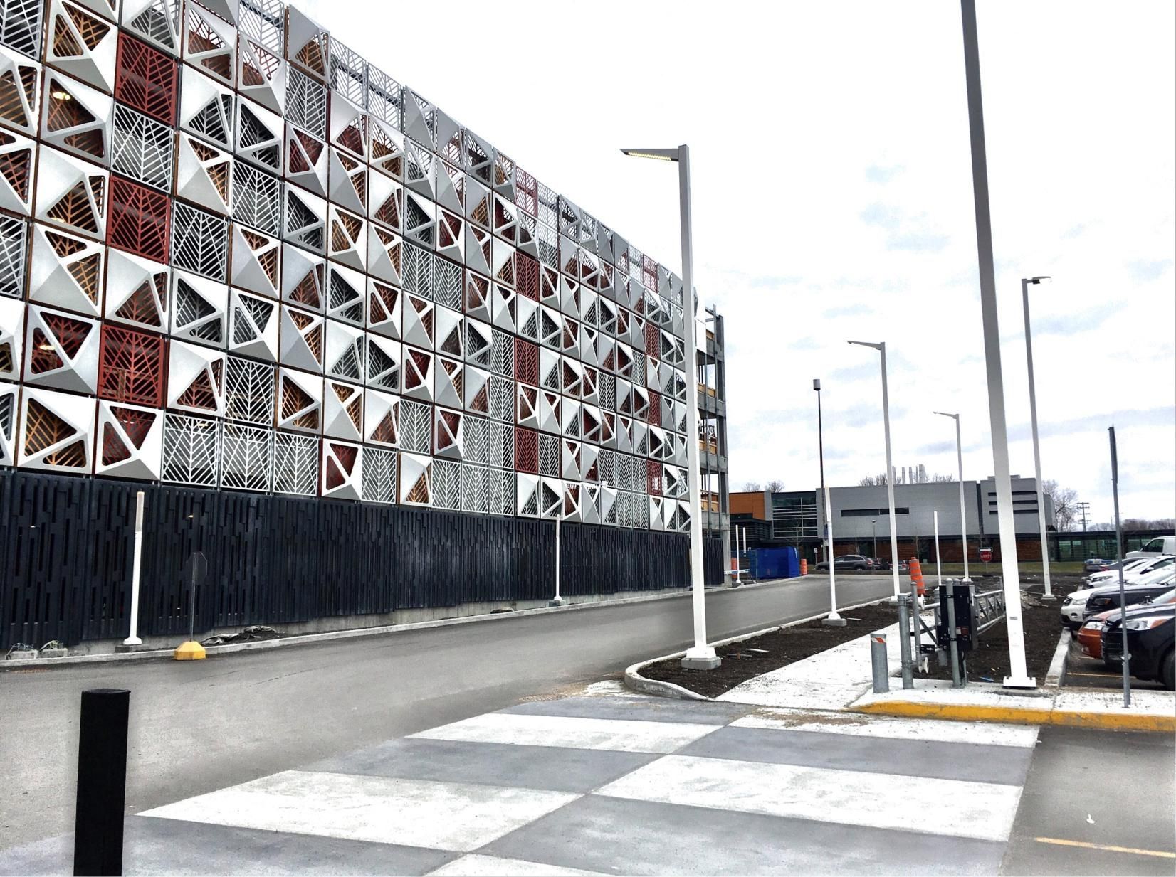Un grand bâtiment avec beaucoup de fenêtres est en construction sur un parking.