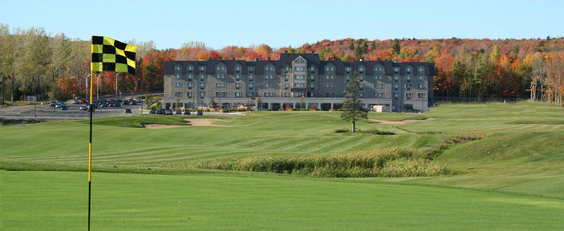 Un terrain de golf avec un grand bâtiment en arrière-plan et un drapeau au premier plan.
